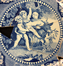 Pearlware saucer printed underglaze in medium blue.  Rim design of scene vignettes. 5.25” rim diameter, 1.25” vessel height .